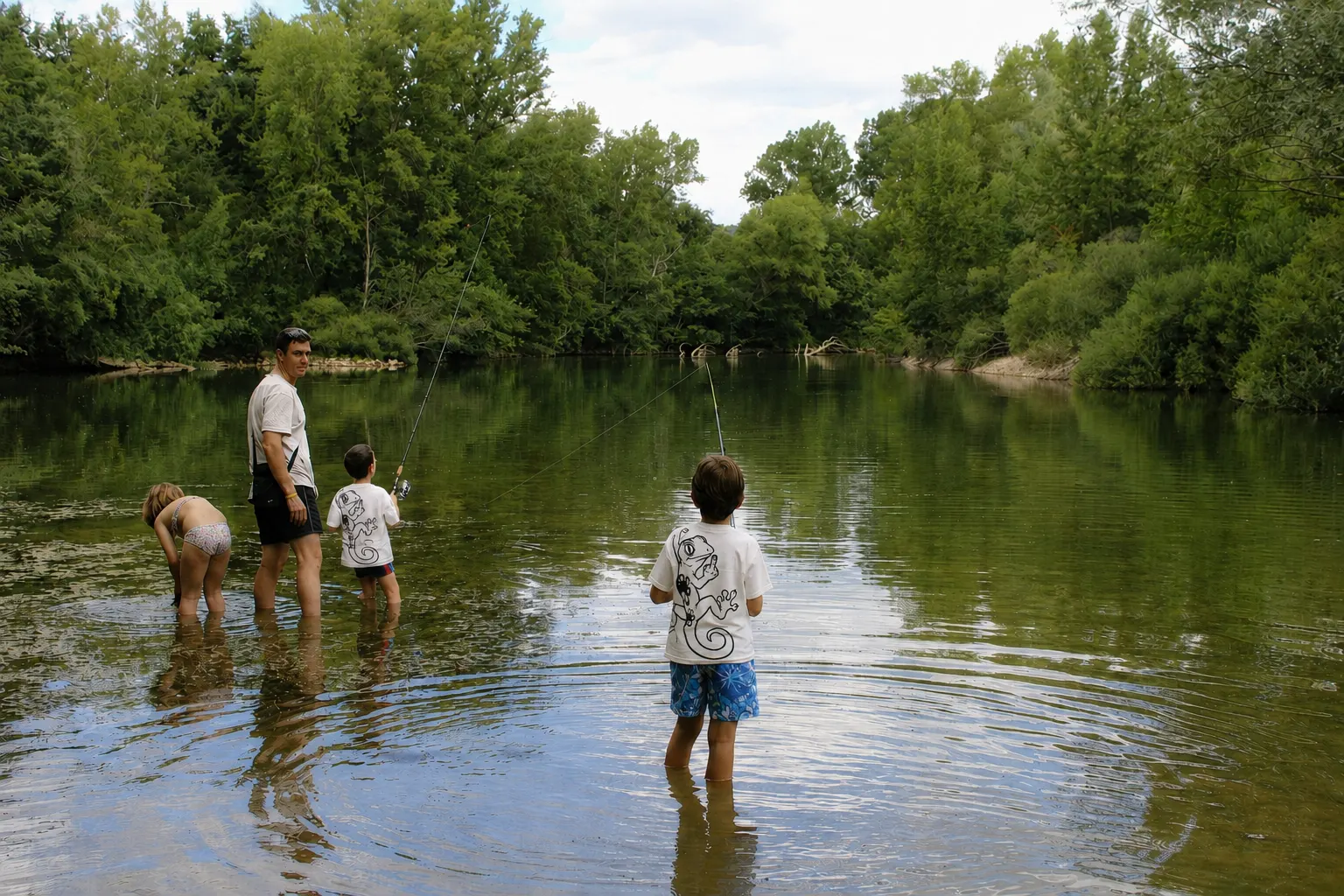 Familia vadeando un río de aguas tranquilas, dos niños con camisetas NONI del lagarto