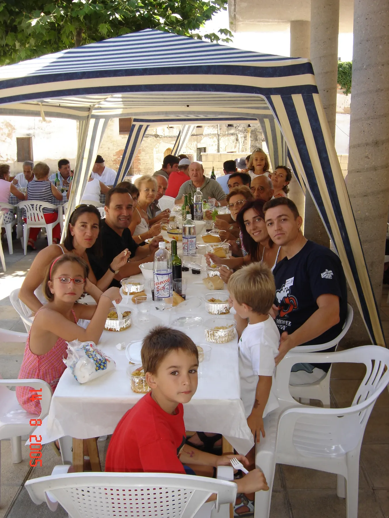 Familia reunida en la comida popular bajo el toldo de las fiestas