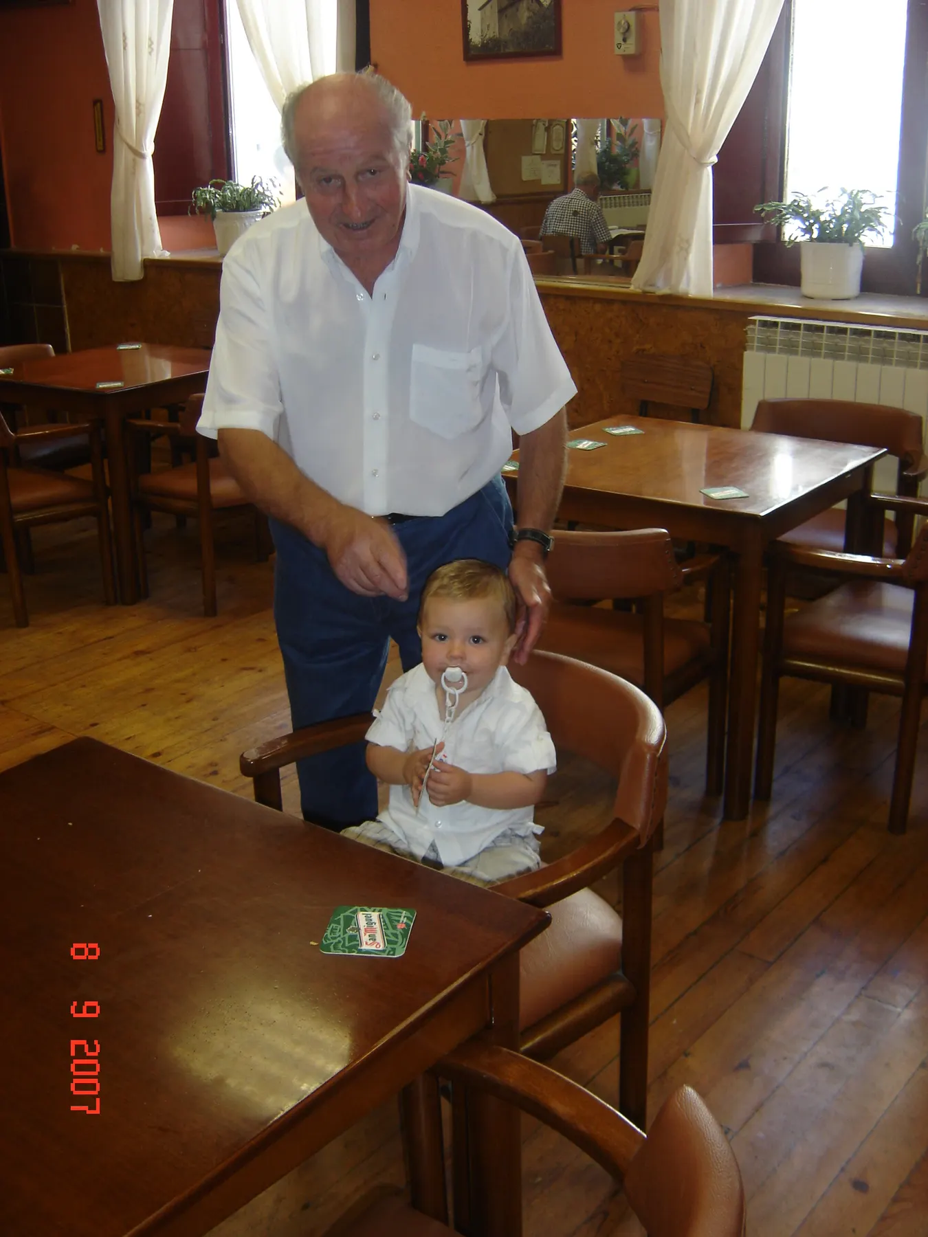Retrato del abuelo con el bebé en el bar del pueblo