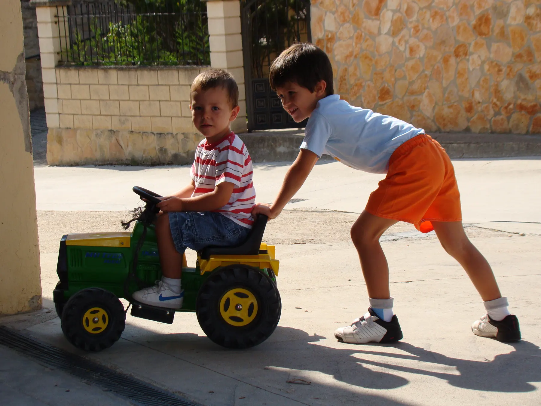 Dos niños jugando con el tractor de juguete en la calle